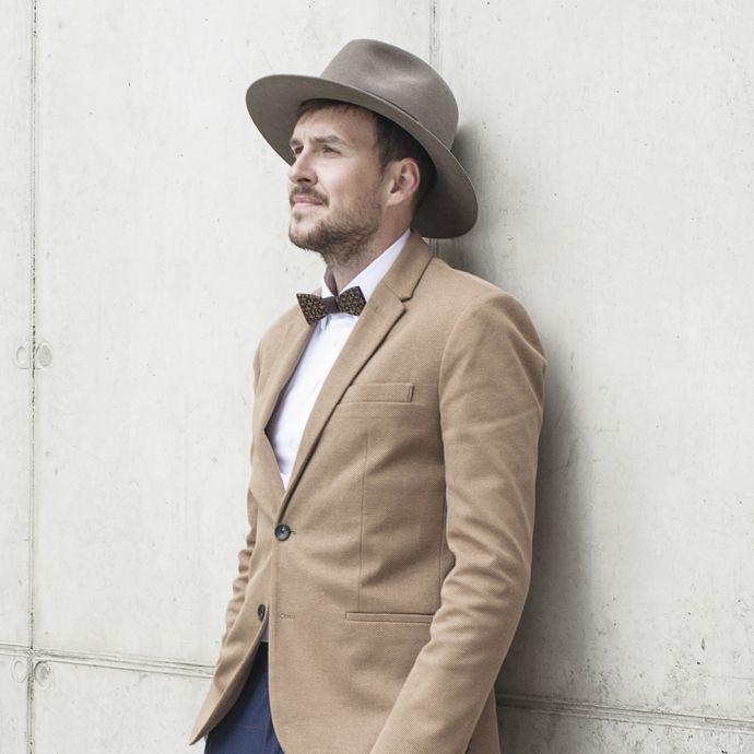 Ein Mann mit braunem Apis Hut mit brauner Jacke