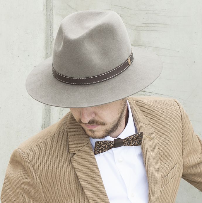 Ein Mann mit braunem Apis Hut mit brauner Jacke
