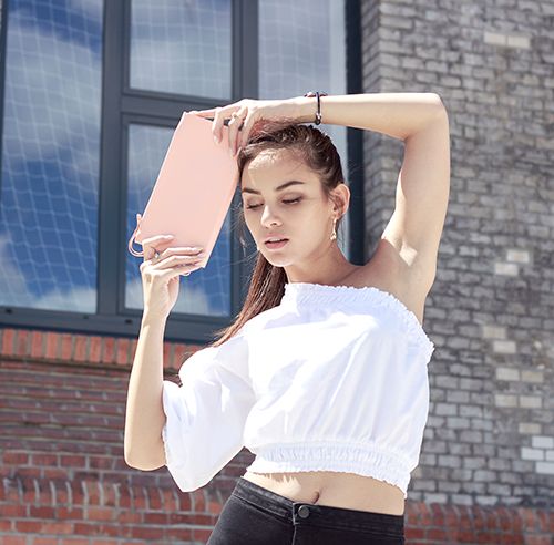 Eine braunhaarige Frau mit einer eleganten Clutch Handtasche aus Leder