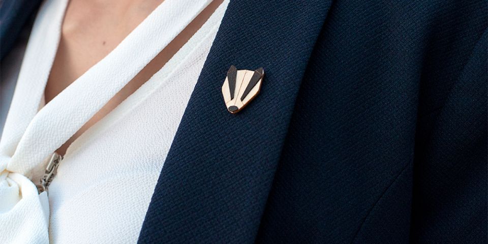 BeWooden - Eine Frau in einer Jacke mit der Holzbrosche Badger Brooch