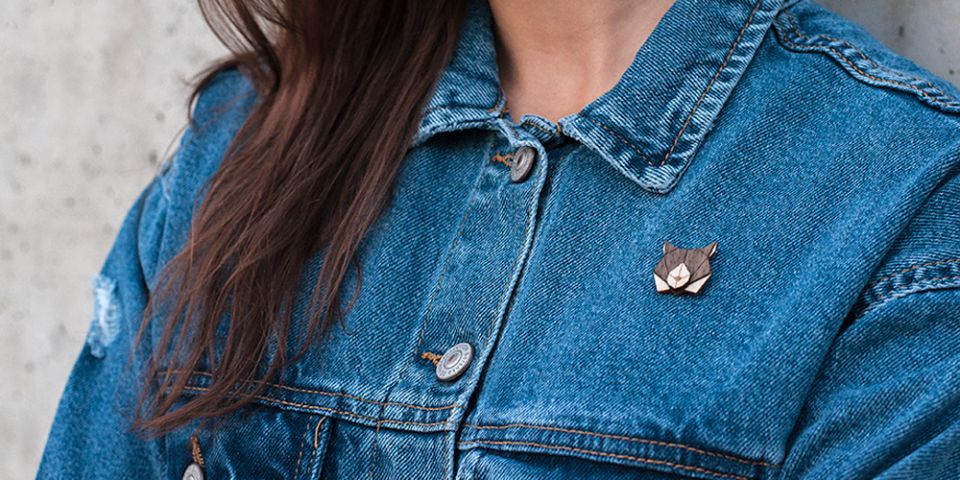 Eine Frau in Jeansjacke mit der Holzbrosche Lynx Brooch