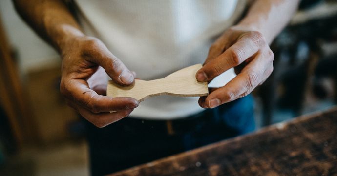 Handwerker aus der Werkstatt mit einer hölzernen Fliege in der Hand