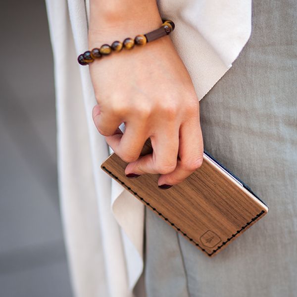 Eine Frau mit dem Kartenhalter aus Holz Nox Note in der Hand