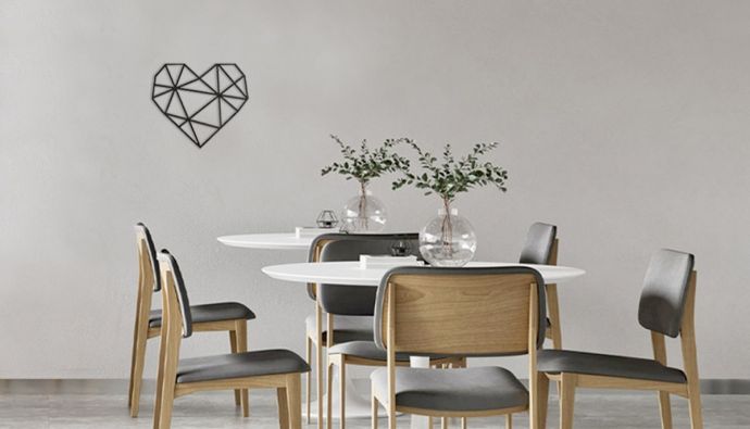 Eine minimalistische Silhouette in Herzform hängt an einer Wand, davor steht ein Esstisch